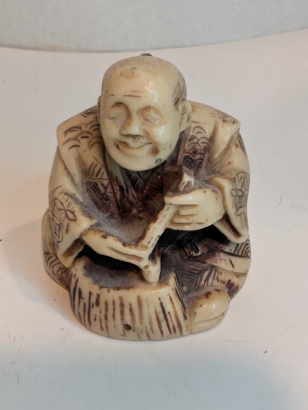 A resin figurine that appears to be a Japanese netsuke depicting a seated man.